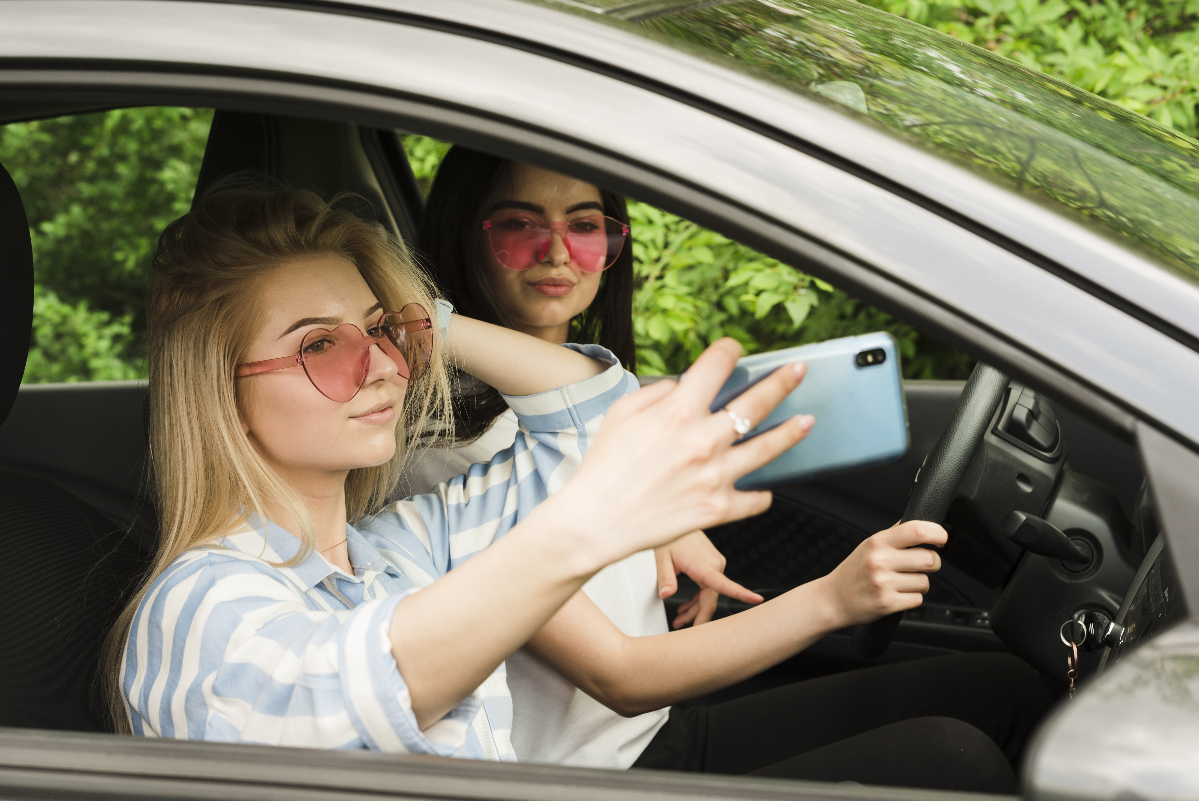 Young driver taking a selfie in the passenger seat of a car.